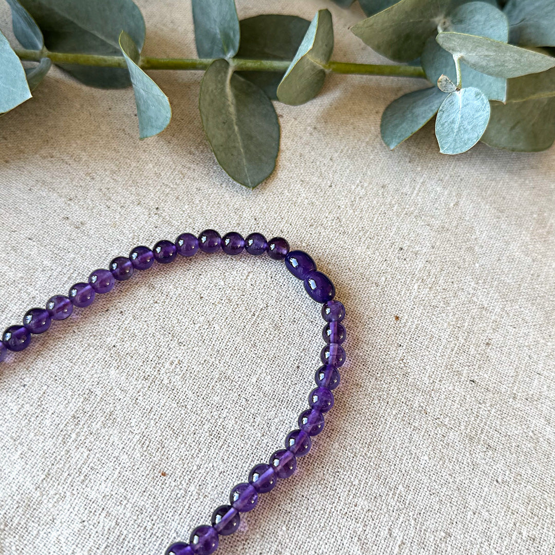 Close-up detail of the barrel clasp and deep purple beads of the Aventari Amethyst Spiritual Power Necklace on linen.