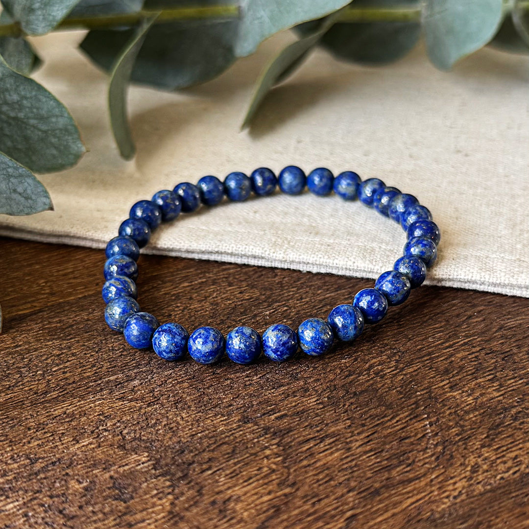 Close-up view of the Aventari Lapis Lazuli Truth Bracelet showing the deep blue beads with pyrite flecks on a wood surface.