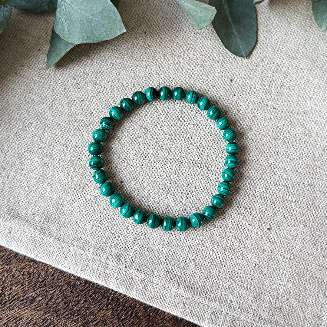 Green banded Malachite Transformation Bracelet by Aventari laid flat in a circle on a textured linen background.