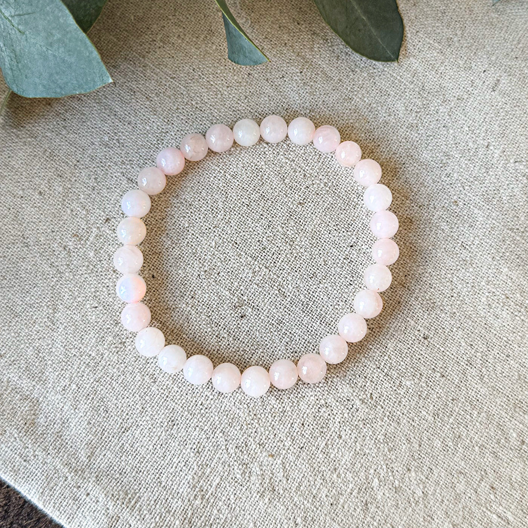 Soft pink Rose Quartz Love Bracelet by Aventari laid flat in a circle on a textured linen background.