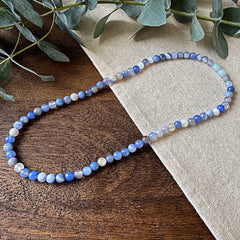 A Blue Lace Agate gemstone necklace handcrafted by Aventari. It's called Blue Lace Agate Communication necklace, because it is said Blue Lace Agate can help with communication. It's a clear top view picture of the necklace. 