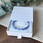 The Blue Lace Agate Communication Bracelet by Aventari, showing its soothing pale blue banded beads inside its white branded gift box.