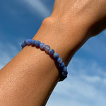 Aventari Blue Lace Agate Bracelet for communication worn on a wrist against a bright blue sky, highlighting its soothing blue hues.