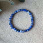 Pale blue banded Blue Lace Agate Communication Bracelet by Aventari laid flat in a circle on a textured linen background.