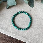 Green banded Malachite Transformation Bracelet by Aventari laid flat in a circle on a textured linen background.